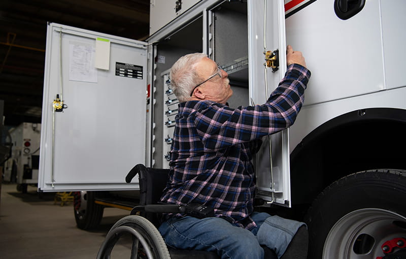 IMT Employee In A Wheelchair Working On Truck Storage Cabinet.