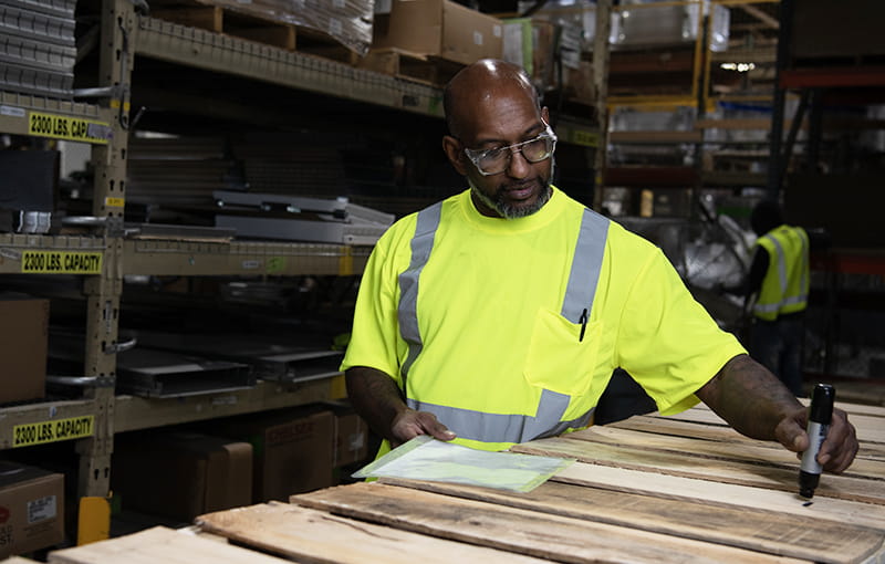 Male Employee Wearing A Neon Green Shirt Taking Inventory.